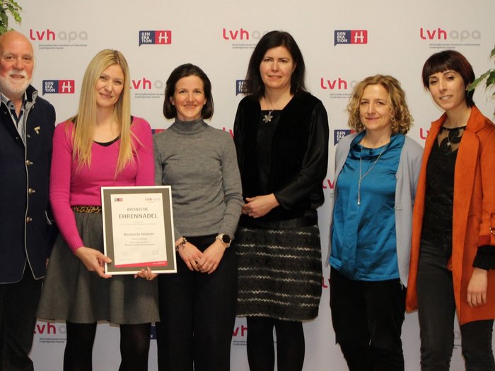 Kleidung wertvoll machen Sechs Personen bei einer Auszeichnung mit Urkunde vor LVH-Apo Hintergrund