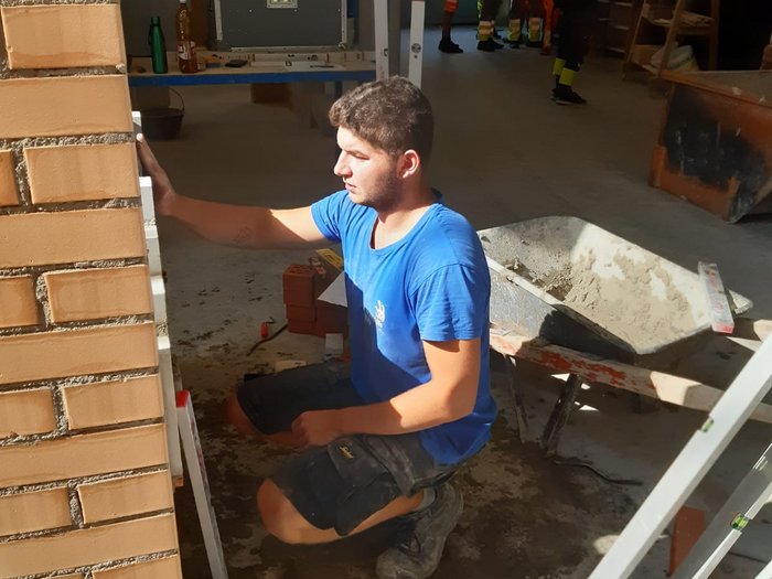 Oliver Stuppner beim Vorbereitungstraining © Foto: Josef Telser Handwerker prüft Mauer mit Wasserwaage in Baustelle mit Gruppe im Hintergrund