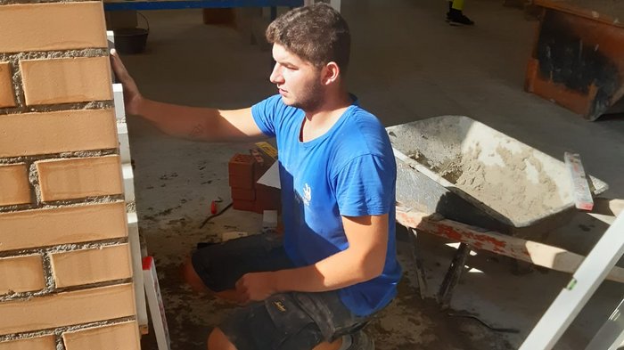 Oliver Stuppner beim Vorbereitungstraining © Foto: Josef Telser Handwerker prüft Mauer mit Wasserwaage in Baustelle mit Gruppe im Hintergrund