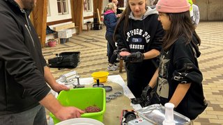 News Personen formen Hackfleisch in einer Halle mit Fleischwolf auf dem Tisch