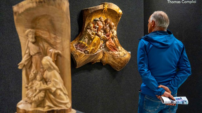La 31^ Fiera d’Arte UNIKA apre le porte a Ortisei Uomo osserva scena intagliata in legno in galleria