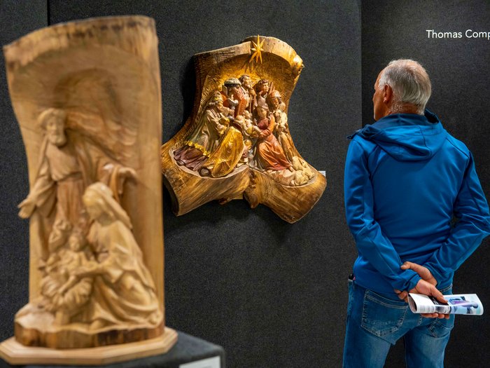 La 31^ Fiera d’Arte UNIKA apre le porte a Ortisei Uomo osserva scena intagliata in legno in galleria