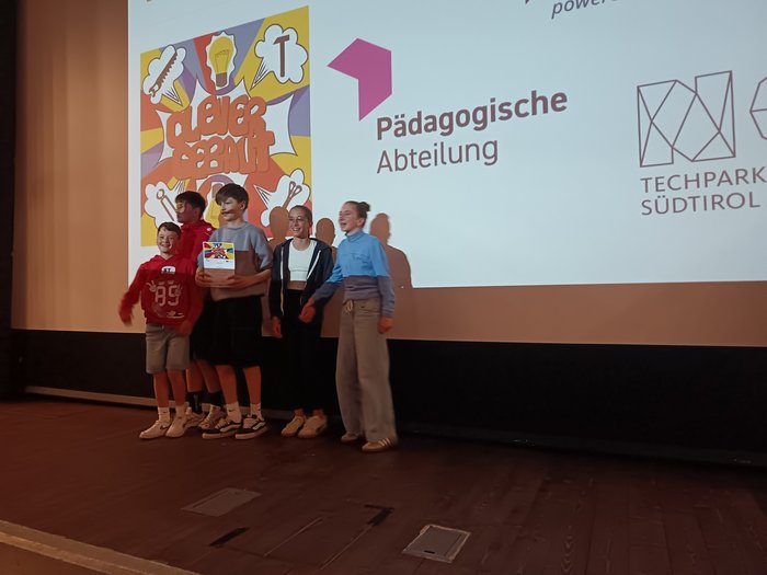 "Clever gebaut": un premio ai giovani creatori più innovativi Cinque bambini sul palco davanti allo schermo con reparto pedagogico e Techpark Alto Adige