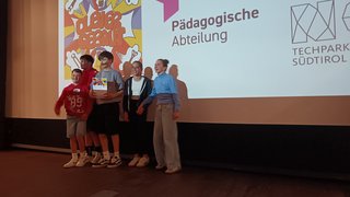 News Fünf Kinder stehen auf Bühne vor Bildschirm mit Pädagogische Abteilung und Techpark Südtirol