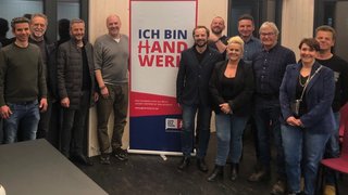 News Gruppe von Leuten steht vor einem Banner mit Schrift ICH BIN HANDWERK