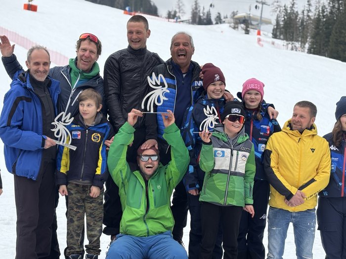 Handwerker/innen tauschen Werkzeuge gegen Skier und Rodel Gruppenfoto mit Skiteam und Gewinnern auf Siegerpodest im Schnee