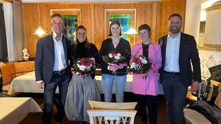 News Fünf Personen stehend in einem Holzinterieur, drei Frauen halten Blumensträuße