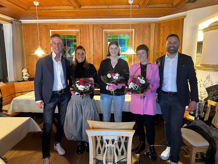 Auf Kooperation, Stärke und Nachwuchsförderung setzen die Funktionärinnen und Funktionäre des neuen Ortsausschusses im lvh. Fünf Personen stehend in einem Holzinterieur, drei Frauen halten Blumensträuße