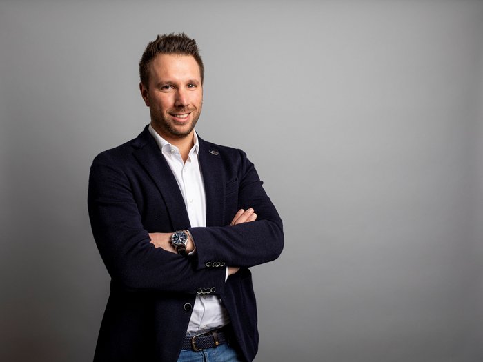 Fritz Ploner neuer Baugruppenobmann im lvh Junger Mann in Anzugjacke vor grauem Hintergrund mit verschränkten Armen