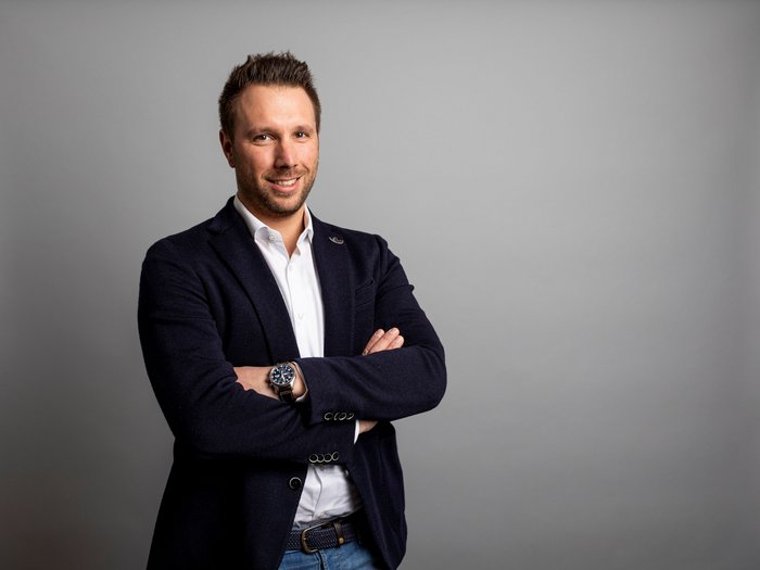 Fritz Ploner nuovo presidente del gruppo edilizia di lvh.apa Giovane uomo con giacca elegante davanti a sfondo grigio con le braccia incrociate