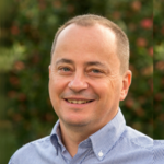 Burggrafenamt Porträt eines lächelnden Mannes vor unscharfem grünem Hintergrund