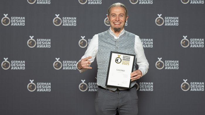 Lobis Böden vince il German Design Award 2025 Uomo sorride tenendo premio German Design Award 2025 davanti allo sfondo