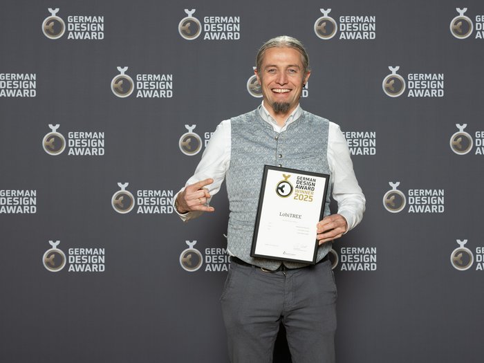 Lobis Böden vince il German Design Award 2025 Uomo sorride tenendo premio German Design Award 2025 davanti allo sfondo