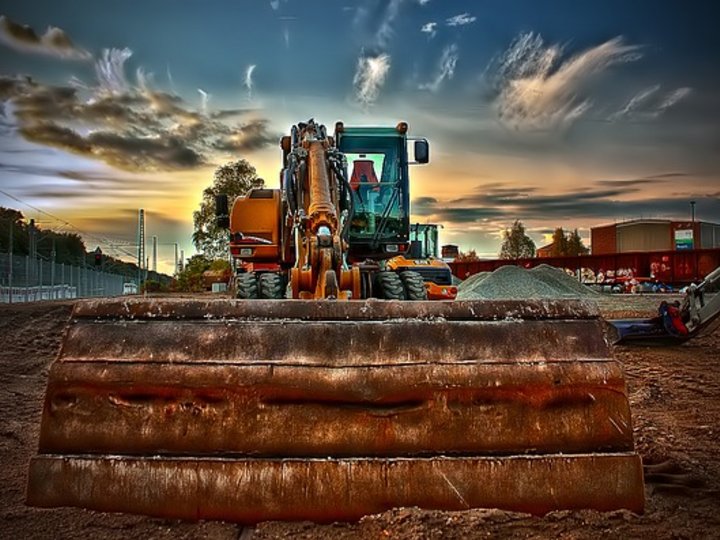 Imprese movimento terra Escavatore con grande benna davanti a cielo drammatico in cantiere
