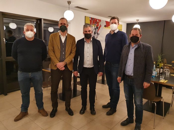 Handwerk: nachhaltig aus Verantwortung Fünf Männer mit Masken stehen in einem Raum mit Tischen und Lampen