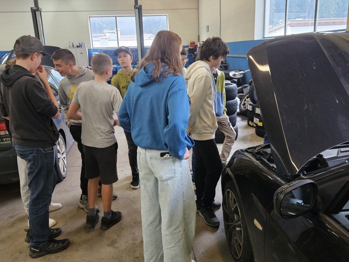 Artigianato come materia a scelta a Sarentino in autunno Gruppo di ragazzi osserva il motore di un'auto in officina