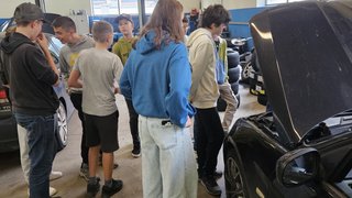 News Gruppe von Jugendlichen betrachtet Motorraum eines Autos in Werkstatt