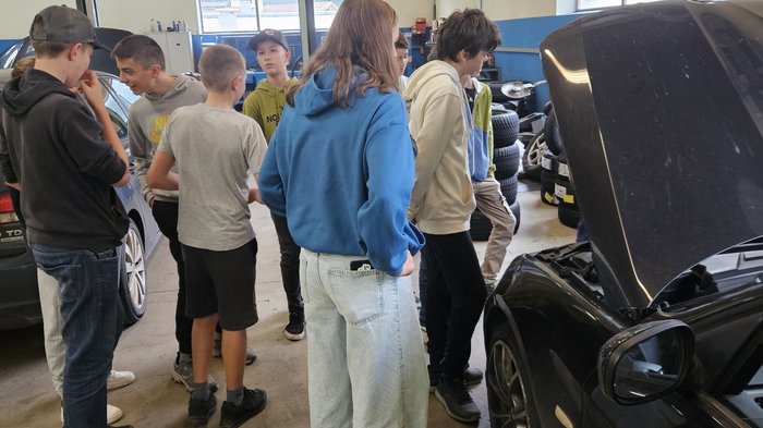 Wahlfach Sarntal im Herbst Gruppe von Jugendlichen betrachtet Motorraum eines Autos in Werkstatt