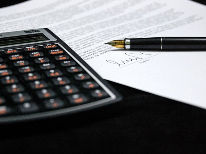 Consulenza fiscale, contabilità e calcolo della busta paga Calcolatrice e firma su un contratto con penna stilografica