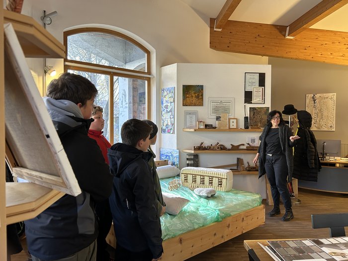 Einblicke in Traumberufe im Handwerk und Gastgewerbe Frau erklärt Kindern in einem Raum mit Holzmöbeln und Kunstwerken