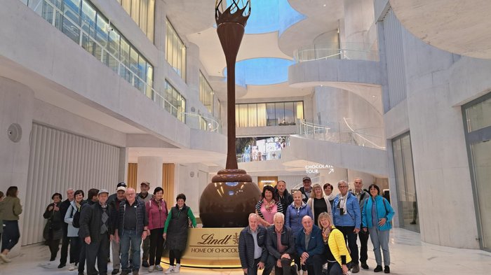 Viaggio autunnale degli artigiani anziani di lvh.apa: puro divertimento e panorama svizzero Gruppo davanti a grande scultura di cioccolato Lindt in edificio moderno