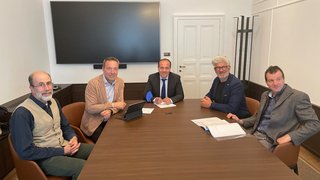 News Fünf Männer in einem Besprechungsraum sitzen an einem Konferenztisch