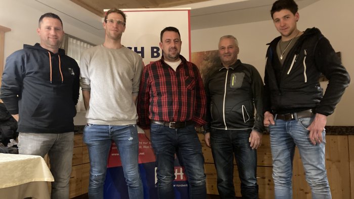 Neuer lvh-Ortsobmann in Mühlwald Fünf Männer stehen in Innenraum vor einem Werbebanner