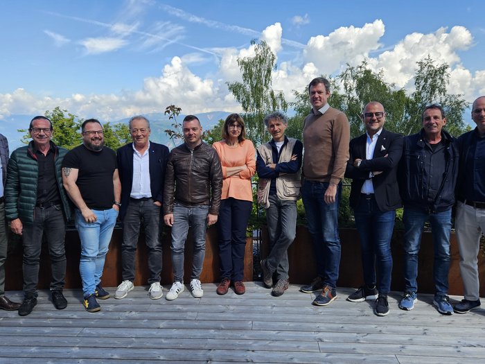 Das Handwerk unterstützt Arbeitnehmende und Familien Zwölf Personen stehen draußen auf Holzterrasse mit Bäumen und Bergen im Hintergrund