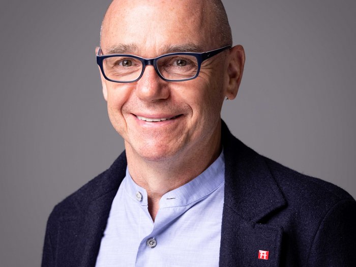 lvh-Direktor Thomas Pardeller © Alfred Tschager Porträt eines lächelnden Mannes mit Brille und dunklem Sakko vor grauem Hintergrund