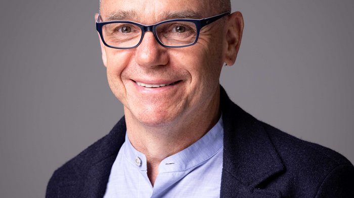 lvh-Direktor Thomas Pardeller © Alfred Tschager Porträt eines lächelnden Mannes mit Brille und dunklem Sakko vor grauem Hintergrund