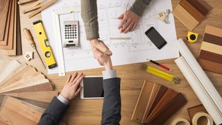 News Zwei Personen schütteln sich über einem Architekturplan die Hände