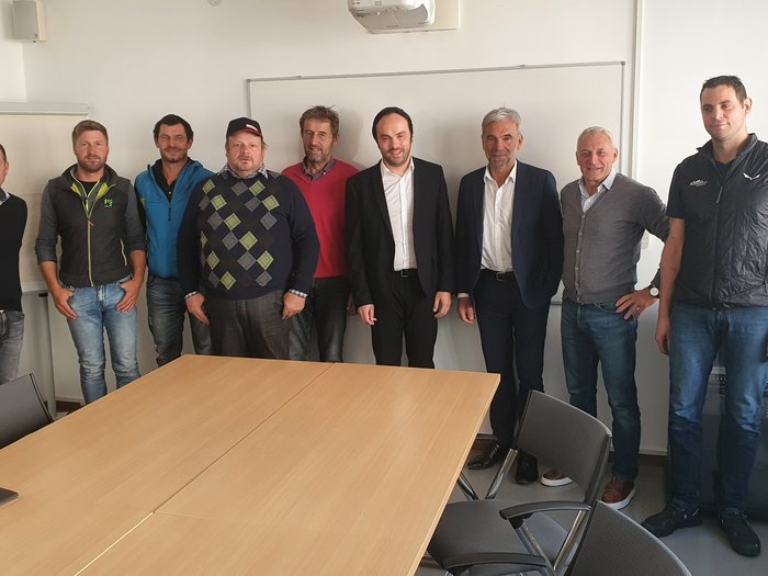 I boscaioli a confronto con gli assessori competenti Nove uomini in una sala riunioni davanti a una lavagna bianca