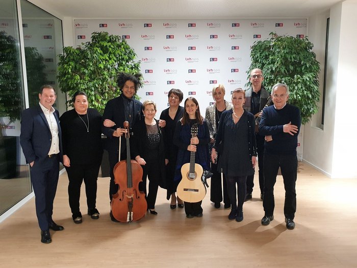 Weihnachtskonzert 2022: Ein besinnlicher Abend Gruppe von zehn Menschen, zwei mit Musikinstrumenten, vor einem LVH-Hintergrund