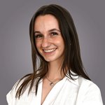 Das lvh-Team Lächelnde junge Frau mit braunen Haaren vor grauem Hintergrund