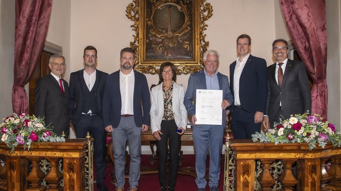 Südtiroler Wirtschaftspreis: Viel Ehre für das Handwerk Sieben Personen in Anzug stehen in einem Raum mit rotem Teppich und Blumen