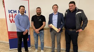 News Vier Männer stehen vor einem Plakat mit der Aufschrift Ich bin Handwerk