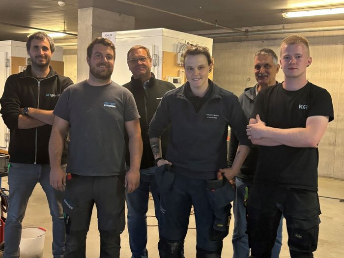 La tecnica non ha genere Cinque uomini in abiti da lavoro scuri posano insieme in un’officina