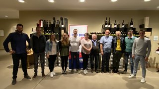 News Gruppe von elf Personen in einem Weinkeller mit Weinregalen im Hintergrund