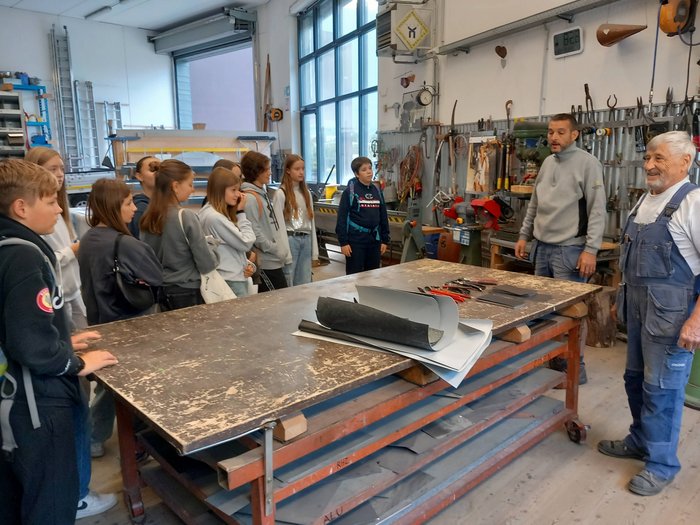SkillsDay Schülergruppe hört in Werkstatt zwei Handwerkern zu