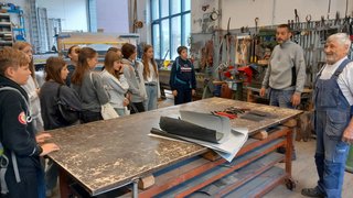 News Schülergruppe hört in Werkstatt zwei Handwerkern zu