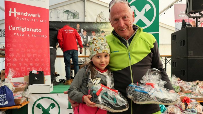 lvh und STA setzen auf lokale Betriebe Älterer Mann und Kind mit Geschenkpaketen bei Handwerksveranstaltung