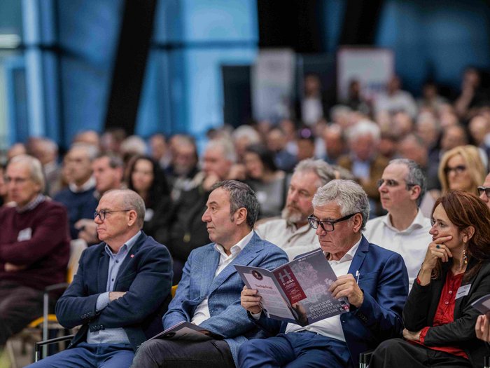 Intelligenza artigiana: nuove opportunità grazie all‘IA Pubblico a una conferenza legge il programma e ascolta attentamente