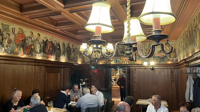 Althandwerker/innen unterwegs: Rundfahrt Weinviertel Gäste sitzen in einem traditionellen Gastraum mit Holzverkleidung und Wandmalereien