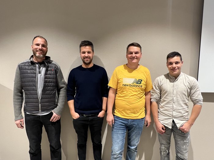 Fliesenleger/innen: Talente im Fokus Vier lächelnde Männer stehen vor einer Wand in legerer Kleidung