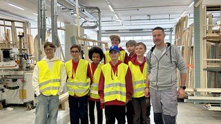 News Gruppe von Kindern mit gelben Sicherheitswesten in einer Werkstatt mit einem Erwachsenen