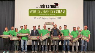 © MirSarner Gruppe von Menschen mit grünen Shirts vor Wirtschaftsschau 2022 Leinwand