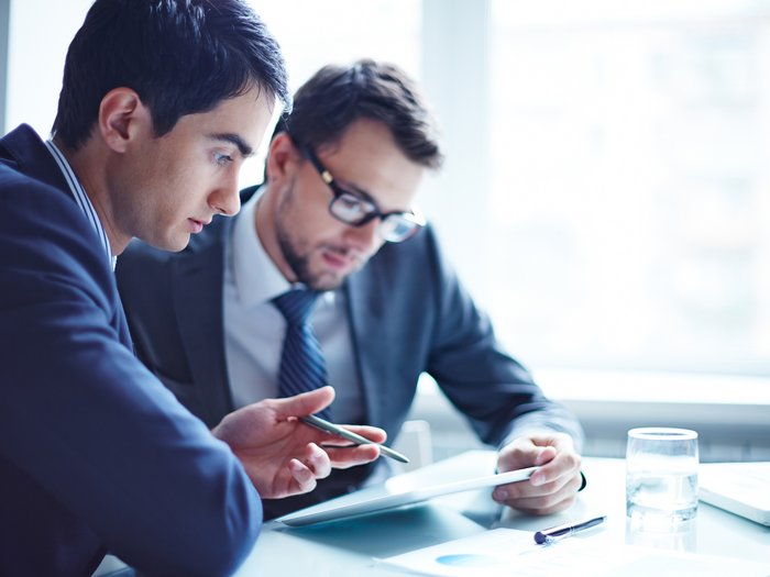 Titolare effettivo: più tempo per la comunicazione Due uomini in abito discutono su un tablet in un ufficio