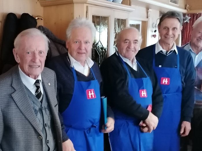 Gli artigiani anziani di lvh.apa festeggiano il loro presidente onorario Sebastian Brugger. Ha compiuto 95 anni. Cinque uomini anziani, tre con grembiuli blu con logo H, in una stanza