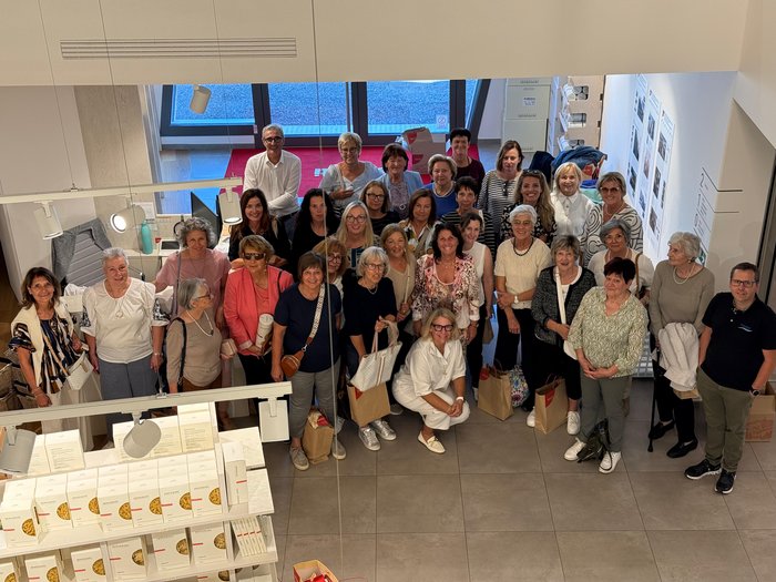 Frauenpower on Tour: Sommerausflug der „Frauen im Handwerk“ ins Fleimstal Große Gruppe von Frauen und Männern, die in einem Raum mit großen Fenstern posieren