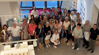 News Große Gruppe von Frauen und Männern, die in einem Raum mit großen Fenstern posieren